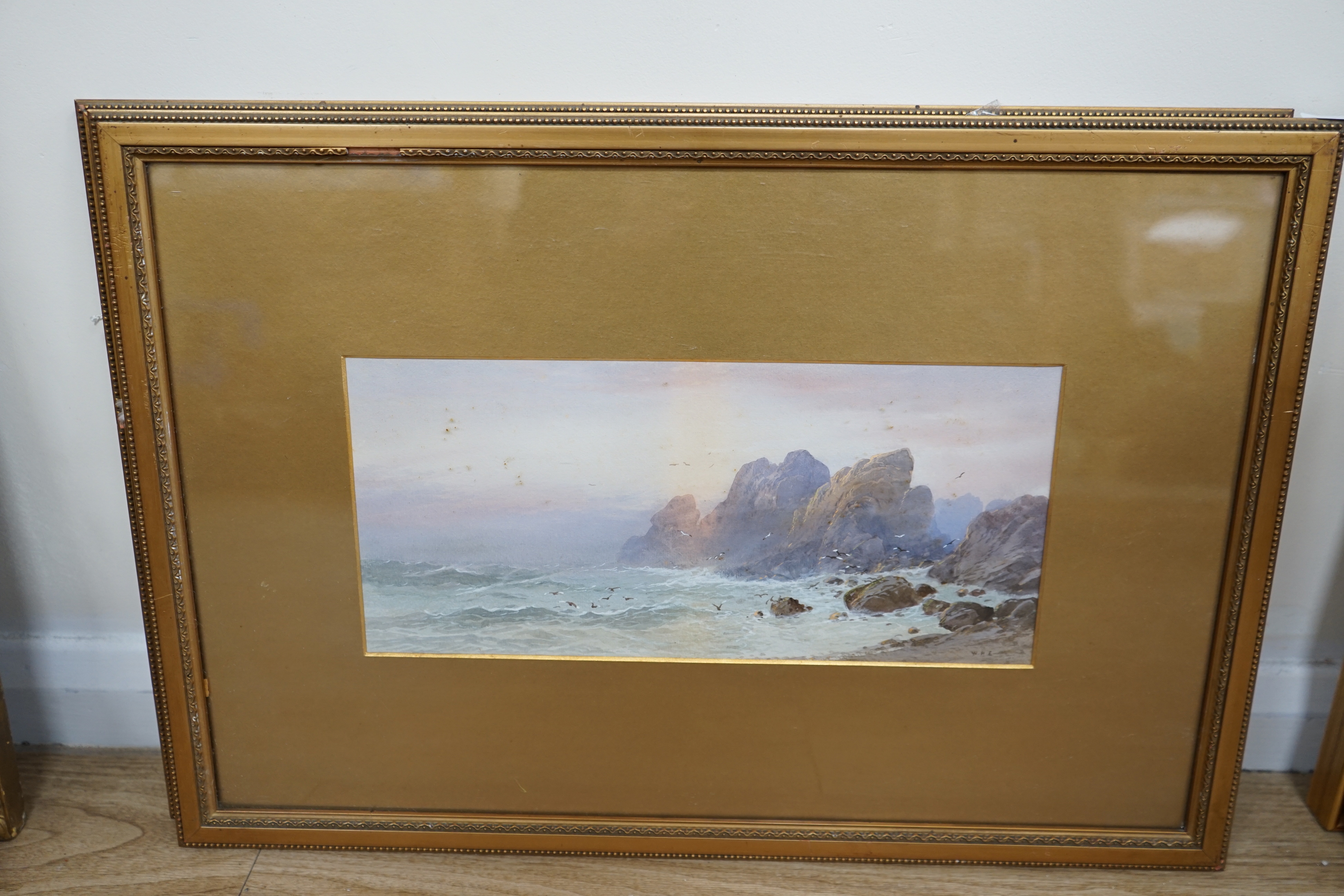 WHE, pair of heightened watercolours, rocky coastal landscapes, signed with monogram, 16 x 36cm